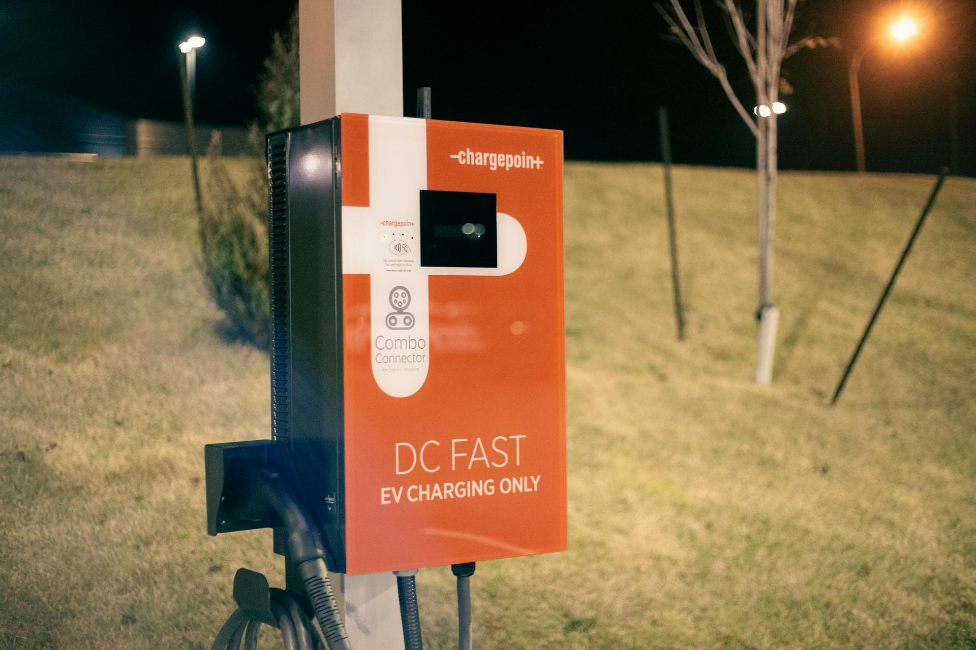 EV charging station at night with a blurred background, offering eco-friendly transportation solutions.