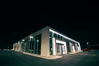 Illuminated building with modern car on parking lot