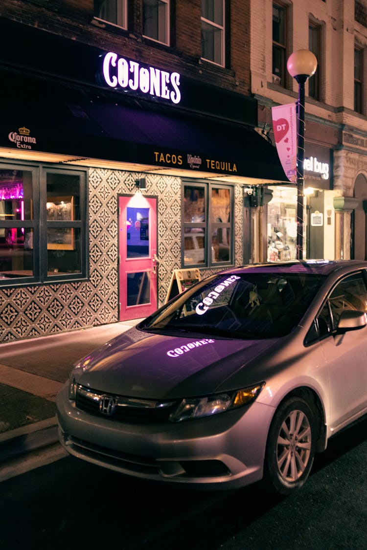 Gray Car Parked On Road Near Building With Glowing Signboard