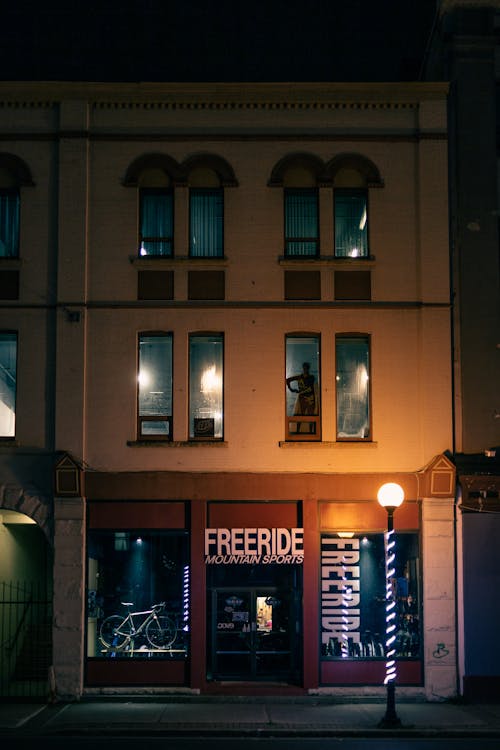 Sidewalk with glowing streetlamp and showcase of store selling bikes and equipment for active sport