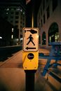 Post with sign for pedestrians showing direction and rule for pressing button before crossing road