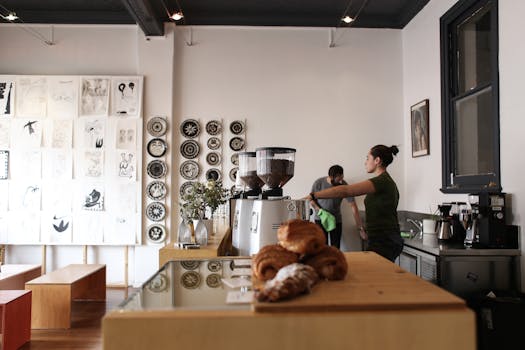 Contemporary cafe interior with art wall, coffee counter, and barista in action.