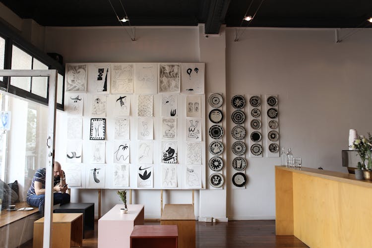 Man Sitting By Reception With Pictures Hanging On Wall