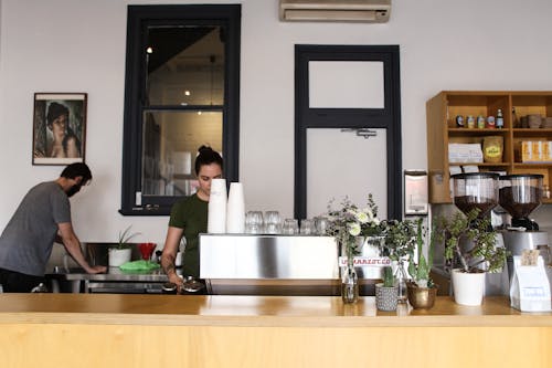 Man Cleaning Coffee Table and Woman behind a Bar