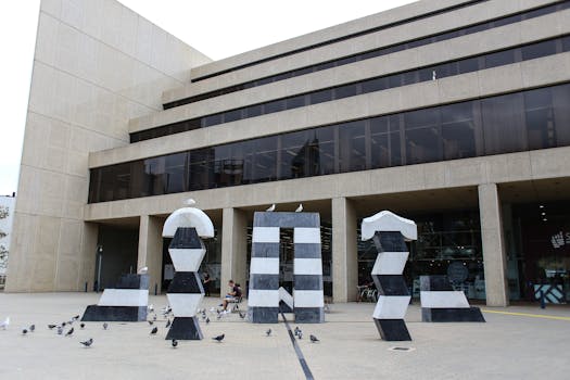 Contemporary building facade with geometric sculptures and pigeons in the courtyard.