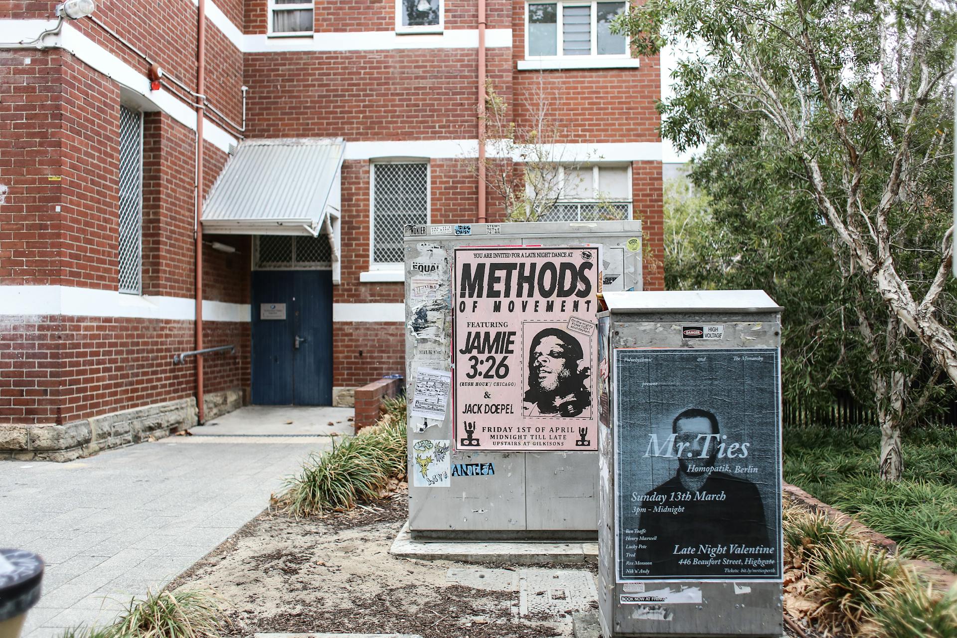 Steel Storage Bins with Posters Outside a Red Brick Wall Building