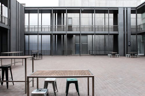 Empty Grey Building Patio with Tables and Stools on a Pavement