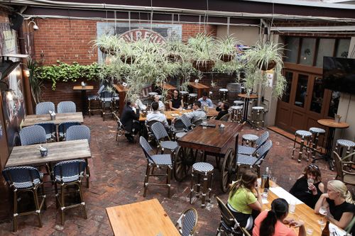 Free Cozy outdoor café setting with patrons enjoying drinks and conversation. Stock Photo