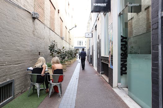 Discover a serene alley café setting with people enjoying a leisurely day. Urban vibe with eateries and shops.
