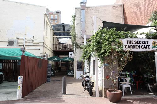 Free Explore the rustic charm of a hidden cafe in a narrow city alley, complete with greenery and a parked motorcycle. Stock Photo