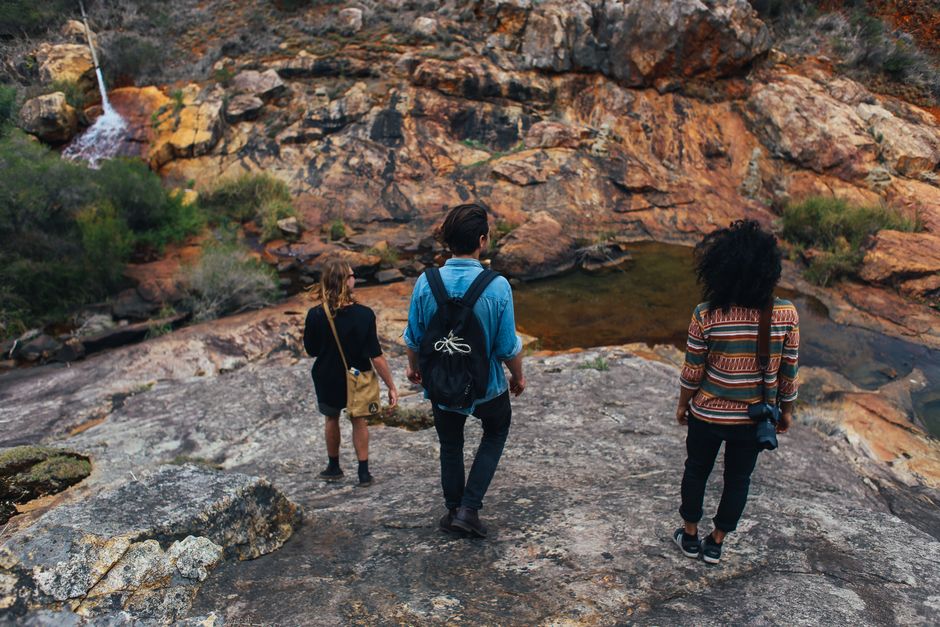 group hiking waterfall trail with backpacks and water bottles - cheap group getaways group hiking waterfall trail with backpacks and water bottles - cheap group getaways