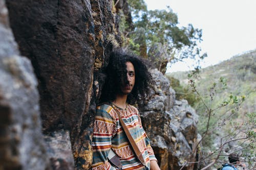 A Man in Printed Shirt Standing Near the Rock Formation