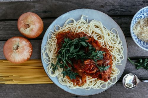 Free Flatlay of spaghetti pasta with rich tomato sauce on a wooden table. Stock Photo