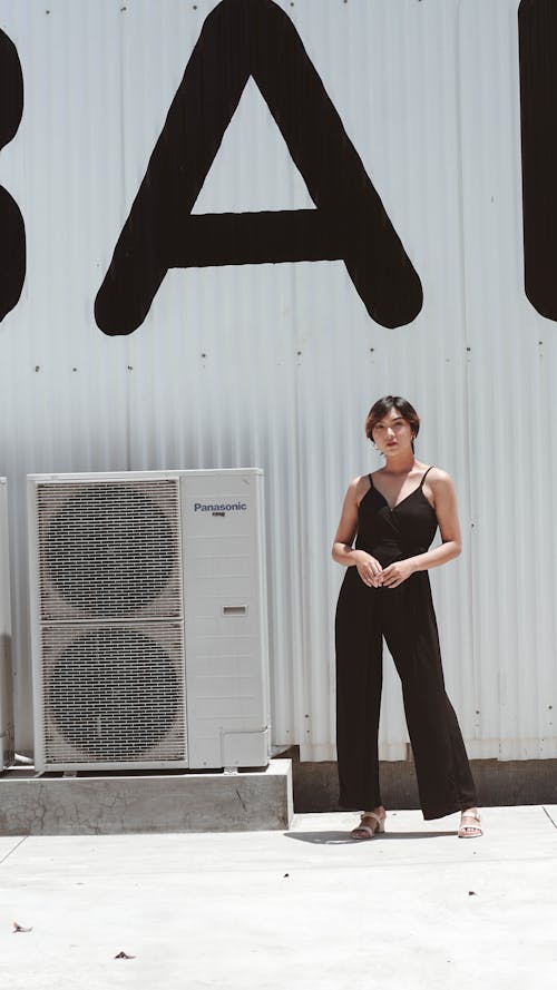 Woman in Black Spaghetti Strap Top and Black Pants Standing Beside White Wall