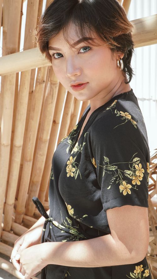 Free Beautiful Indonesian woman in a floral dress posing outdoors with bamboo background. Stock Photo