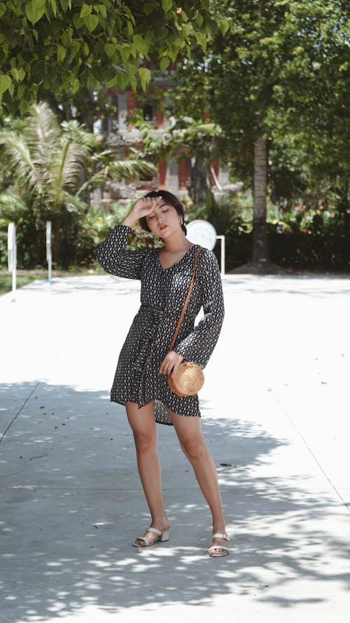 Woman in Black Long Sleeve Dress Standing on Concrete Ground