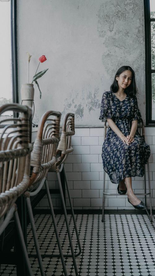 Free Woman enjoying a serene moment in a cool-toned Bali café with chic decor. Stock Photo
