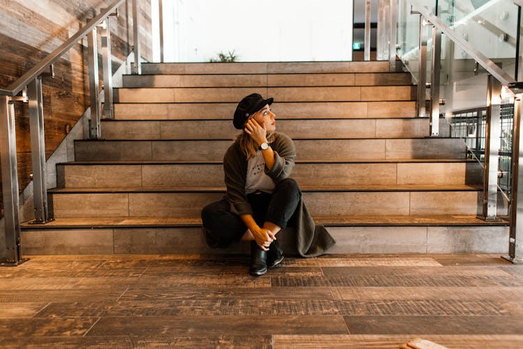 Symmetrical View Of Woman In Hat And Gown Sitting On Steps