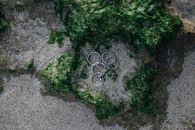 从空中俯瞰，沙滩上绿色海藻中的一枚银色戒指静静搁置