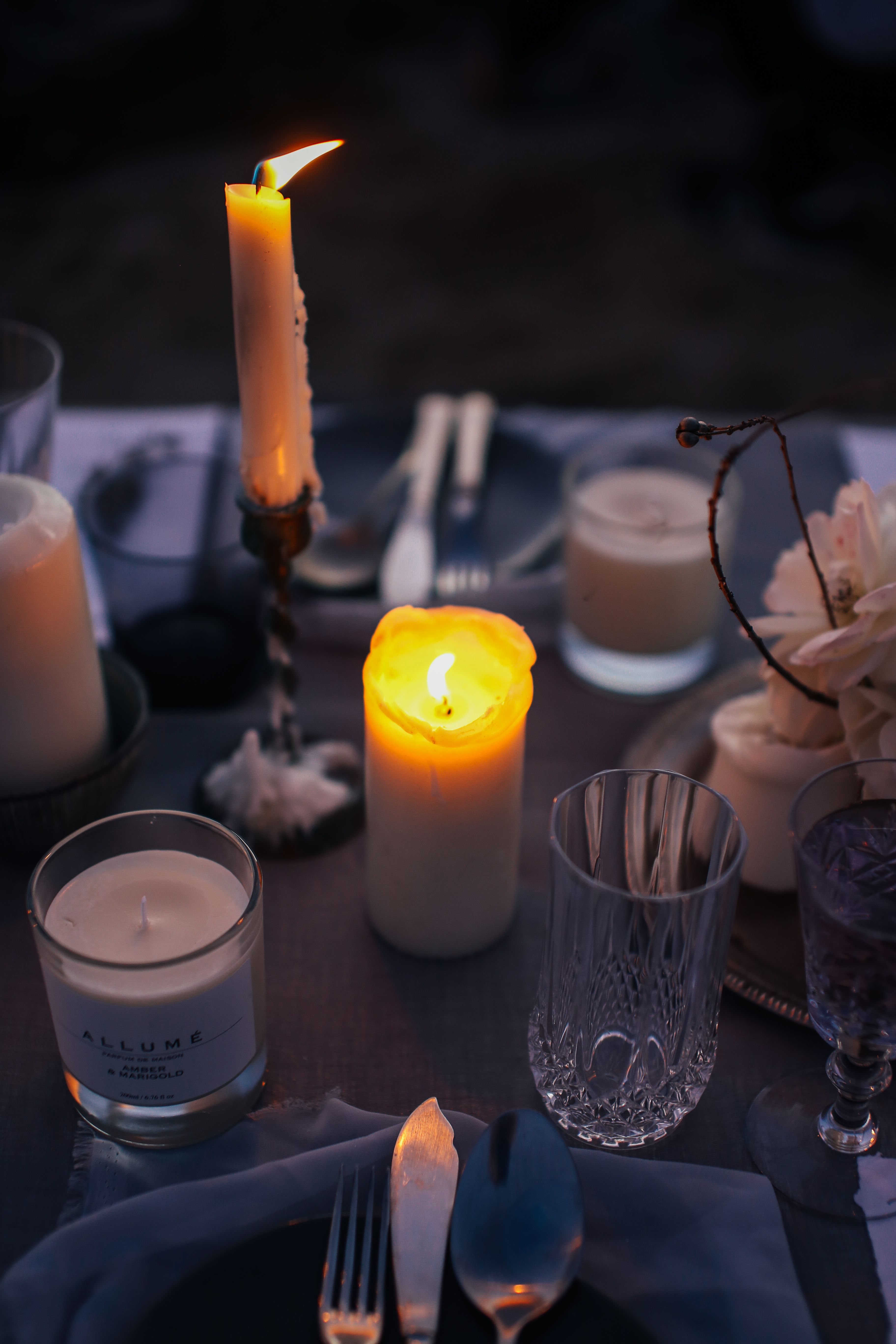 A close-up view of an elegantly decorated dinner table with glowing candles and fine glassware.