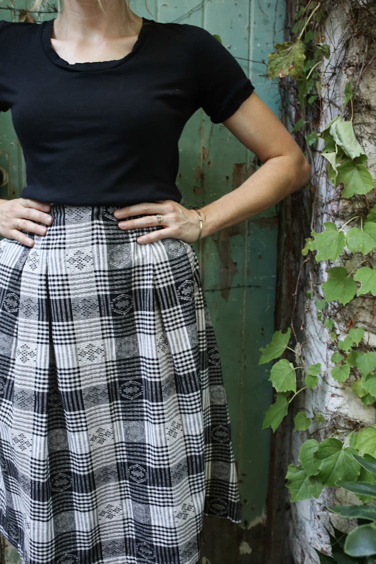 Woman In Black Shirt And Plaid Skirt With Hands On Hips