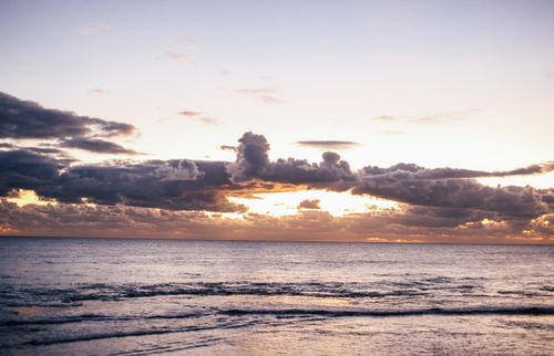 Free Tranquil ocean scene with clouds and sunset glow, perfect for relaxation themes. Stock Photo