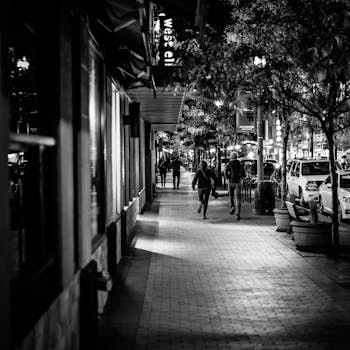 Black and white photo of people walking on a city street at night.