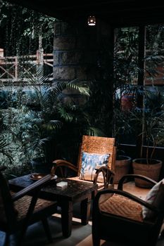 Serene patio featuring wicker chairs, table, and lush plants under ambient lighting. - Fotografer Sidoarjo