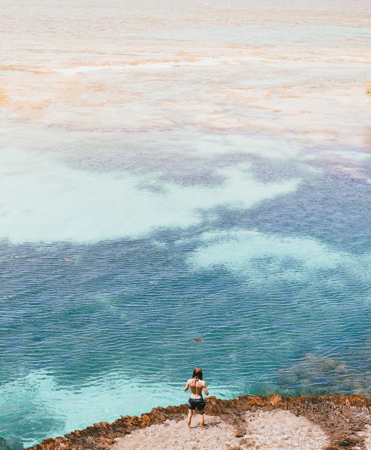 Man Standing On Cliff Overlooking Sea