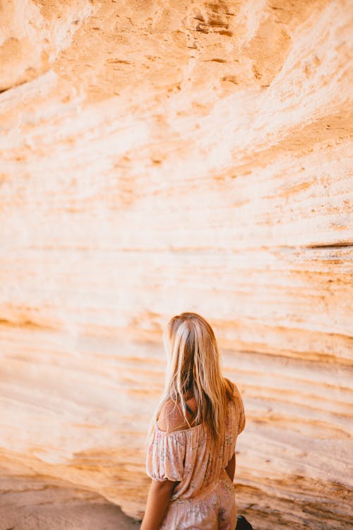 Woman in Floral Dress Standing Near Rock Formation