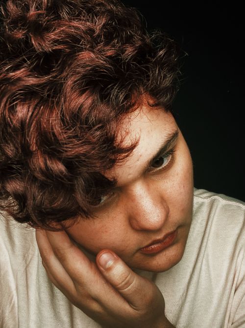 Free Close-up portrait of a young man with curly hair and introspective gaze. Stock Photo