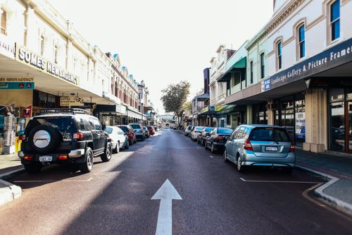 Free Vibrant city street with parked cars and local shops on a sunny day. Stock Photo
