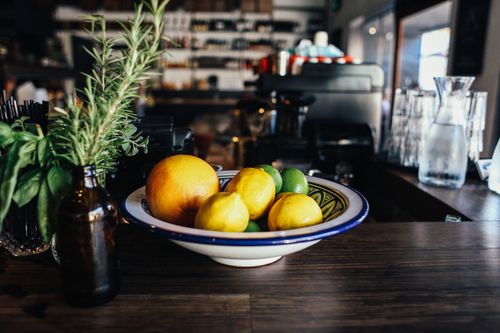 Free A colorful mix of lemons, limes, and oranges in a bowl on a kitchen worktop with rosemary and basil. Stock Photo