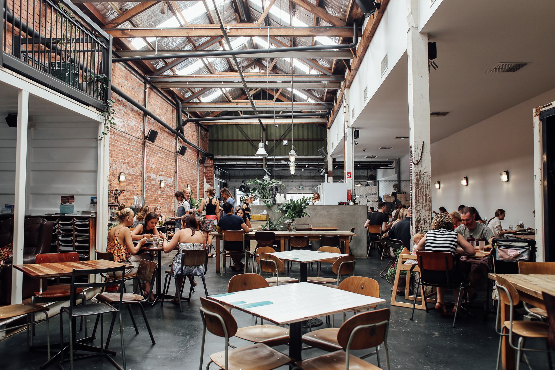 Modern bistro with industrial decor, brick walls, and dining tables filled with people.