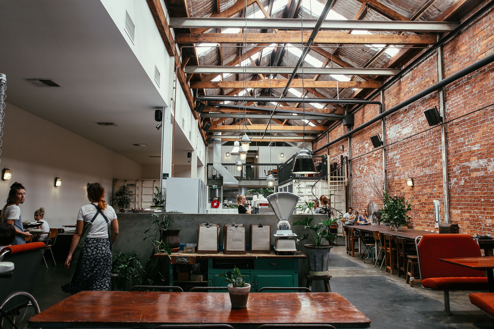 A spacious modern restaurant interior with exposed brick walls, wooden beams, and stylish seating.