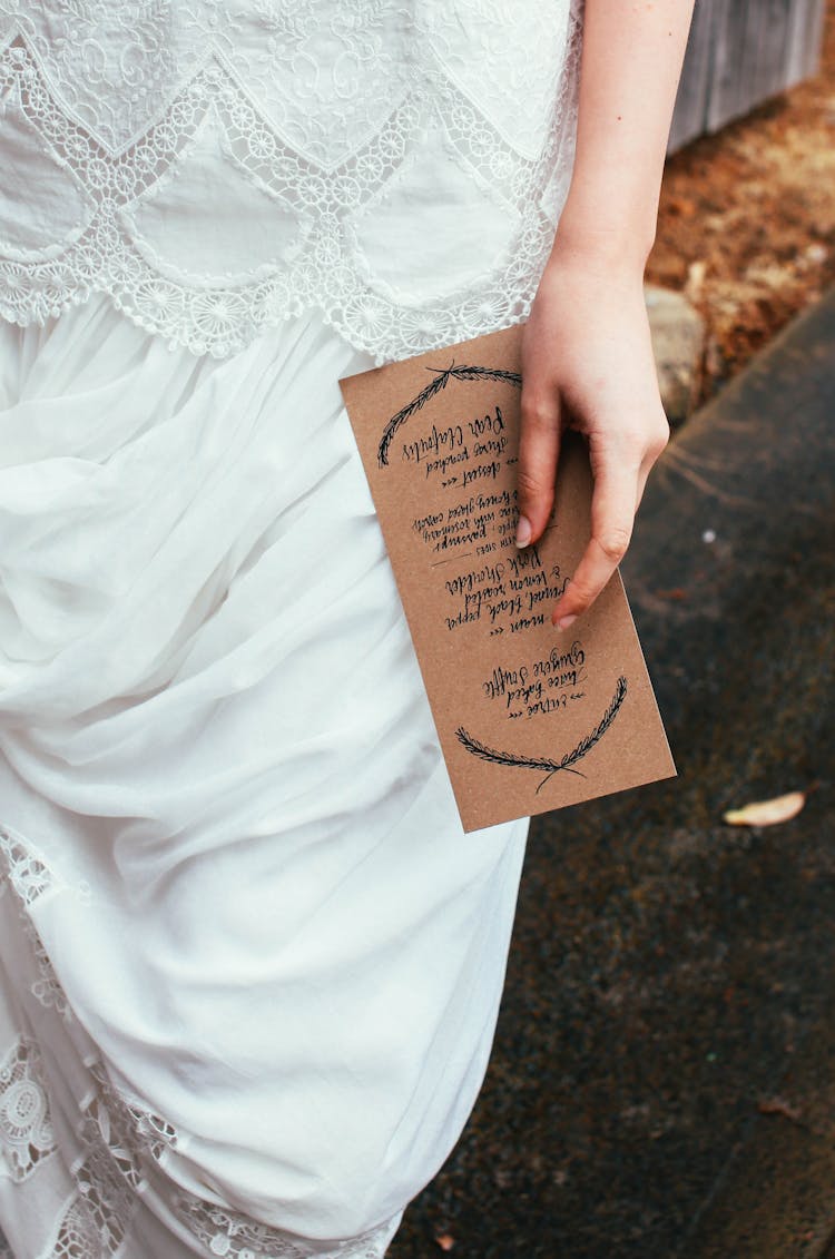 Close Up Of Bride Holding Invitation In Hand