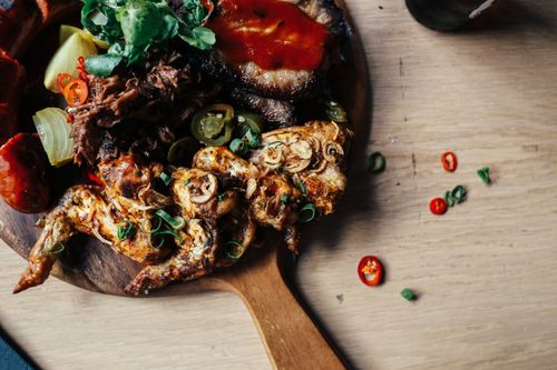 Free A top-view of roasted chicken with vegetables, sauce, and spices, served on a wooden board. Stock Photo
