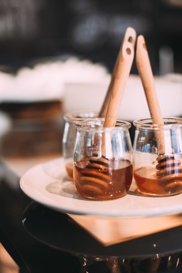Glass jars of amber syrup with wooden dippers — photo by Rachel Claire on Pexels
