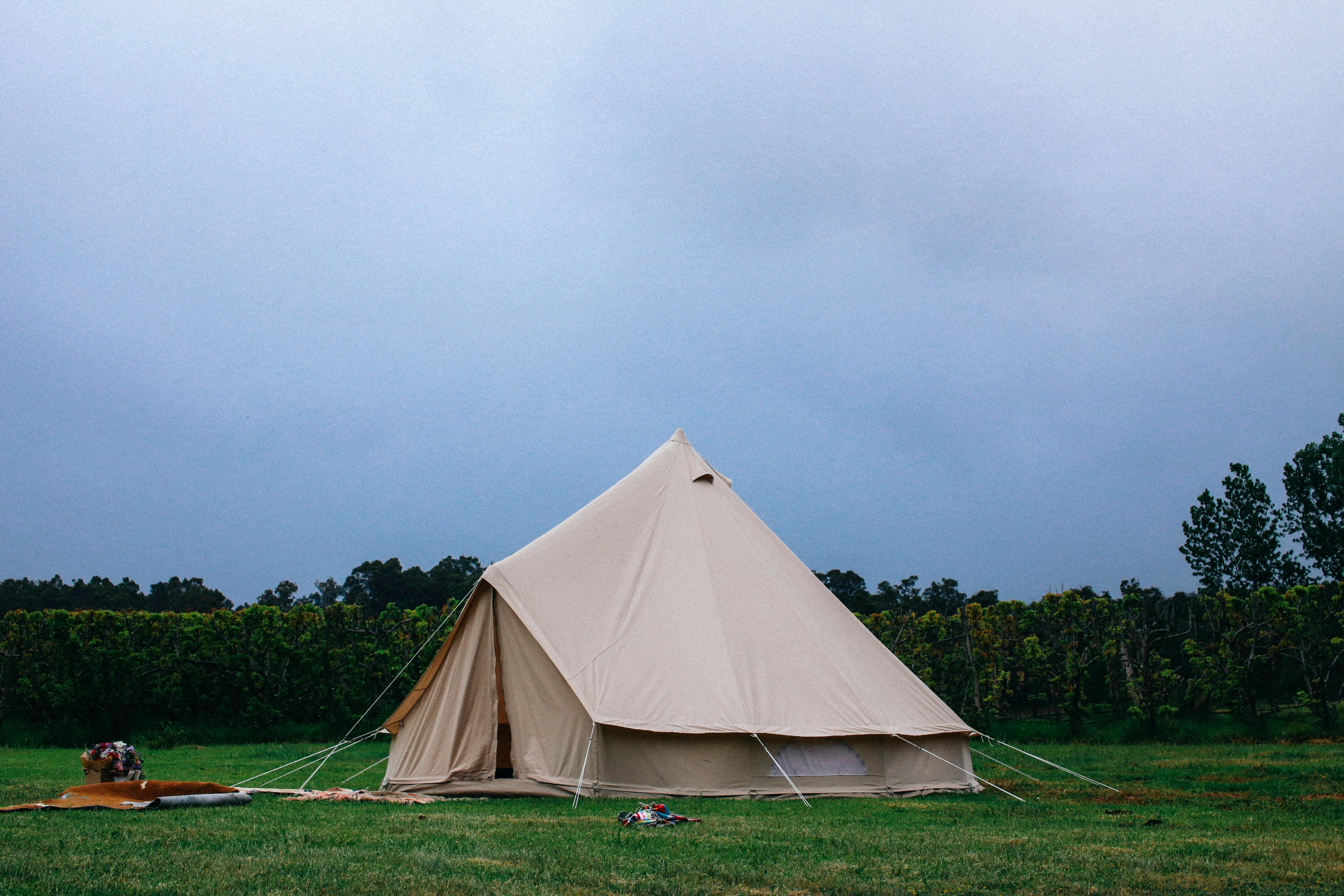 A spacious tent set up on green grass under a cloudy sky, perfect for outdoor adventures.