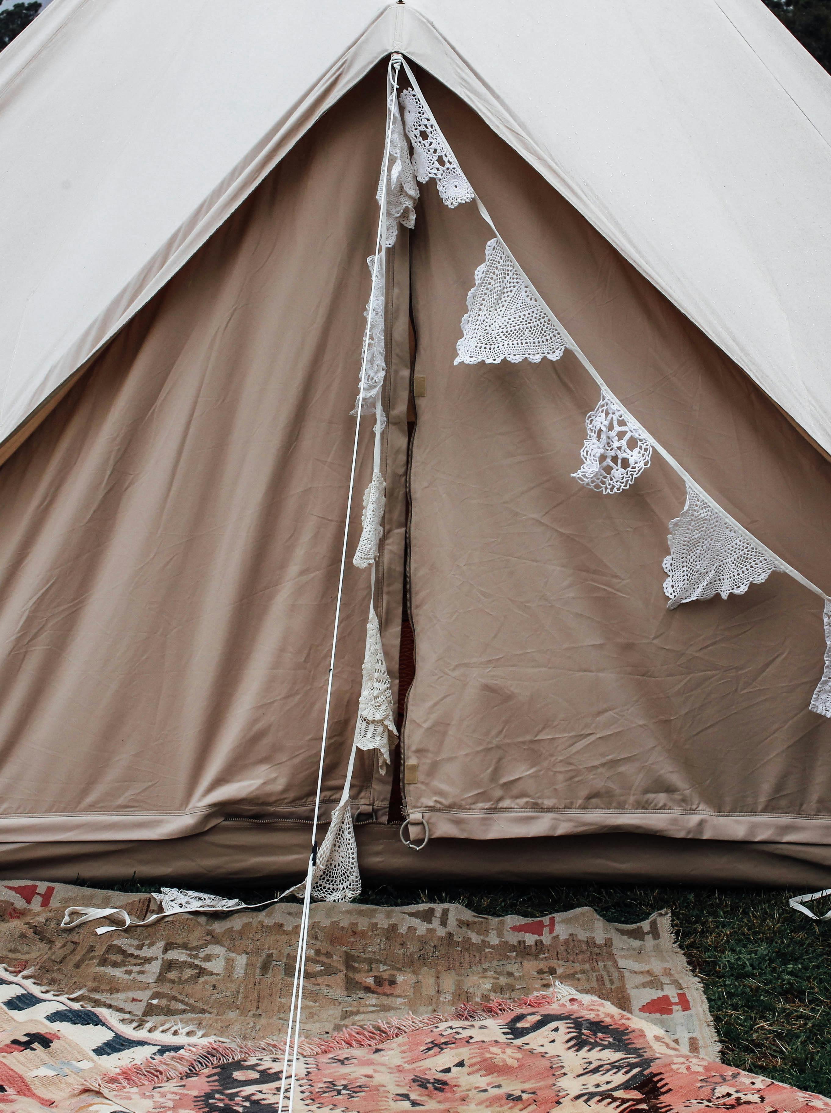 Beige tent adorned with lace garlands, perfect for a romantic outdoor camping setup.