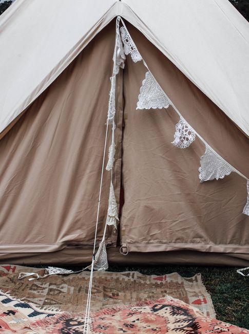 Beige tent adorned with lace garlands, perfect for a romantic outdoor camping setup.
