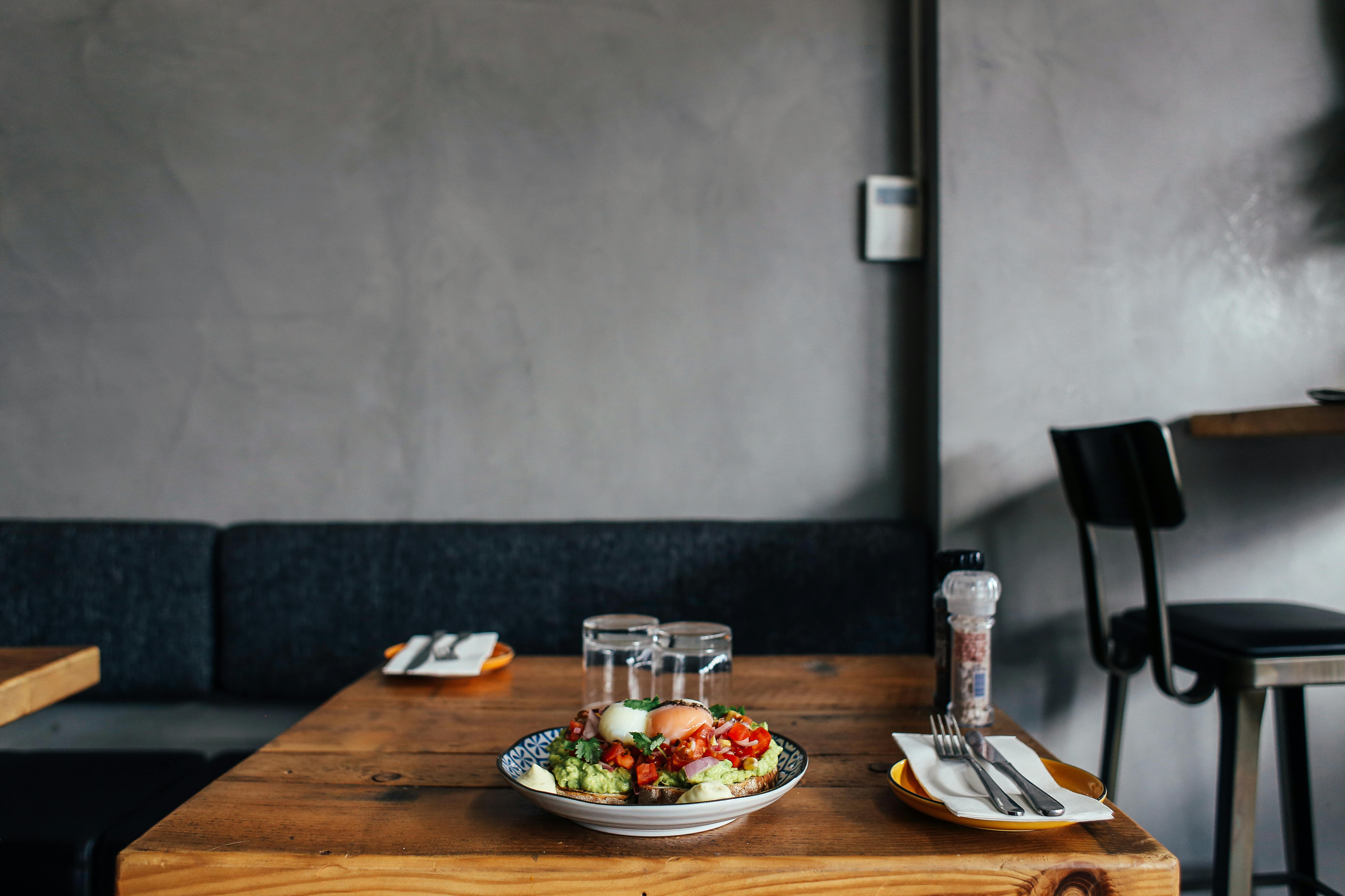 Cozy restaurant table with a contemporary avocado dish and elegant tableware.