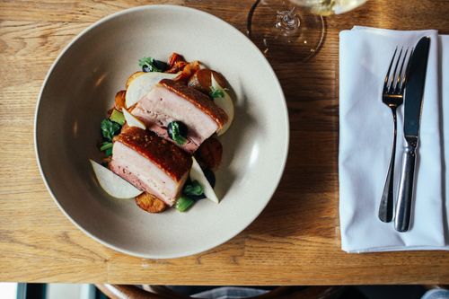 Free Savor a gourmet pork dish with fresh vegetables, artfully plated for a fine dining experience. Stock Photo