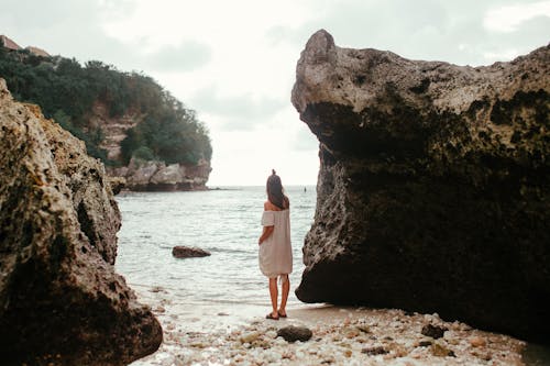 Free Woman in White Dress Standing Near Rock Formation  Stock Photo