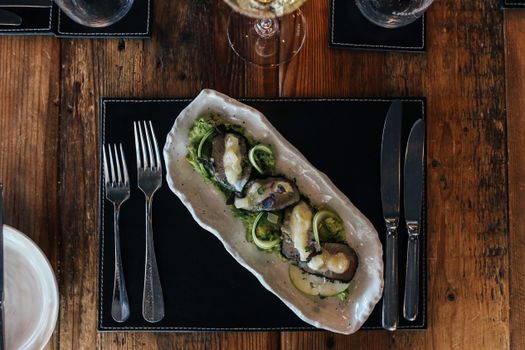 A beautifully plated oyster dish with greens served on a rustic wooden table, perfect for fine dining stock photos.