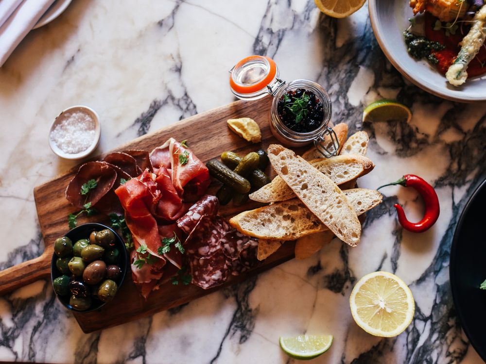 Charcuterie board of cured mountain meats, cheeses, olives and bread