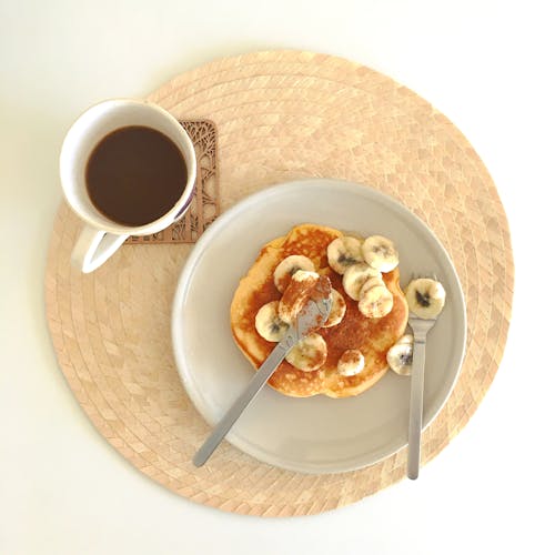 A Piece of Pancake with Banana Slices  and a Cup of Beverage