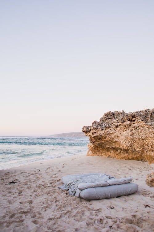 Free Matres with Bed Linen on Airy Sandy Beach Stock Photo