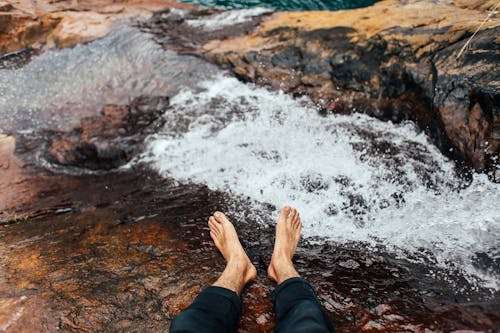 Free Person's Feet Resting on the Rocky River Stock Photo