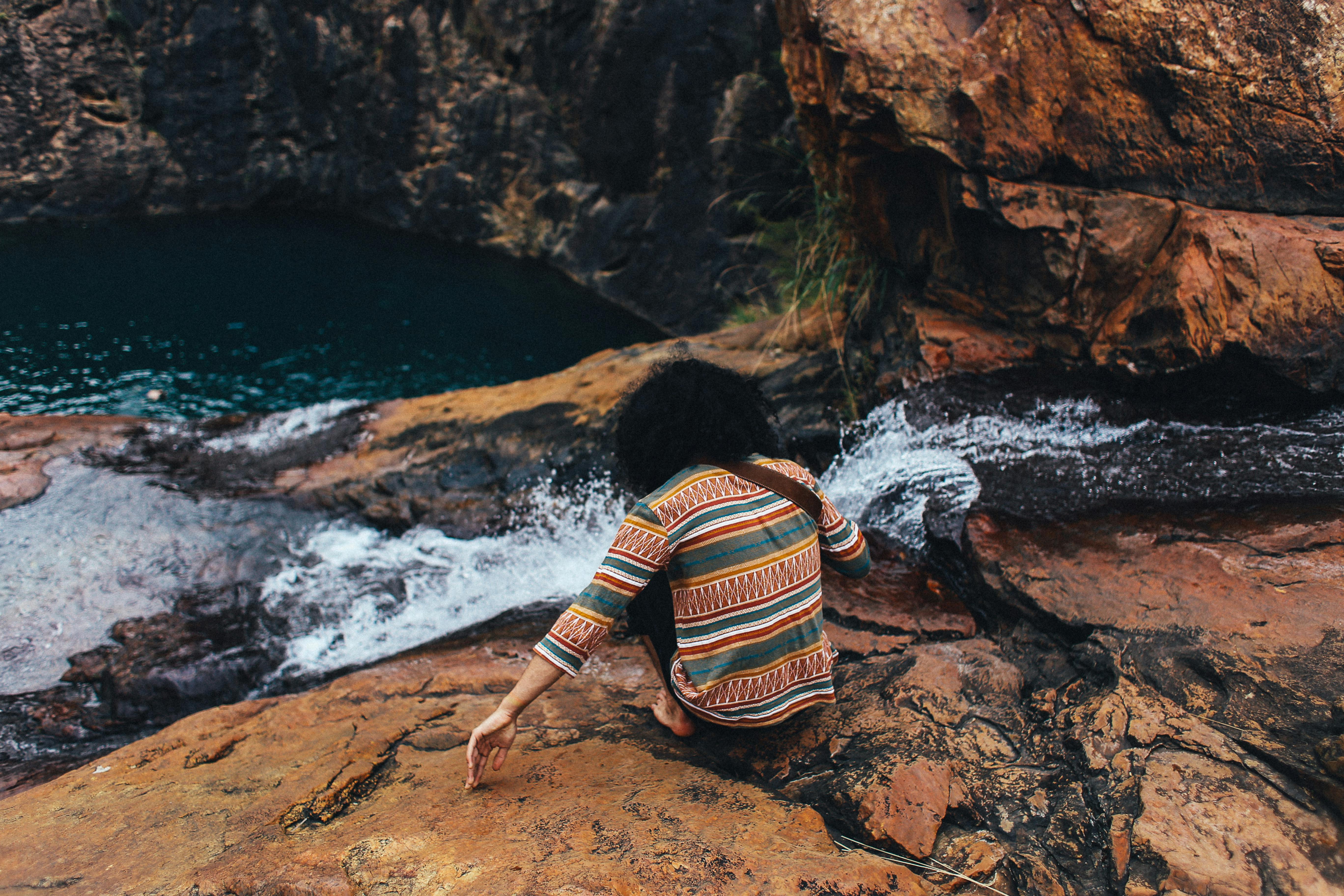 在岩石峡谷的瀑布旁，一个身着彩色服装的人正享受着户外活动